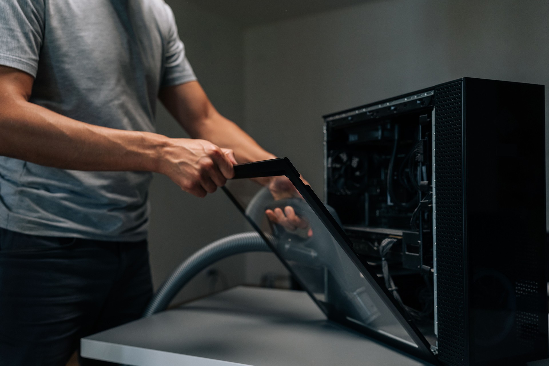 Technician using vacuum cleaner to remove dust and debris from inside computer case, performing essential maintenance for optimal performance.